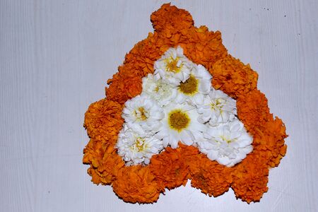 marigold and chrysanthemum flower love heart shape design, rangoli, floral art, traditional decoration with natural flower on white backgroundの写真素材