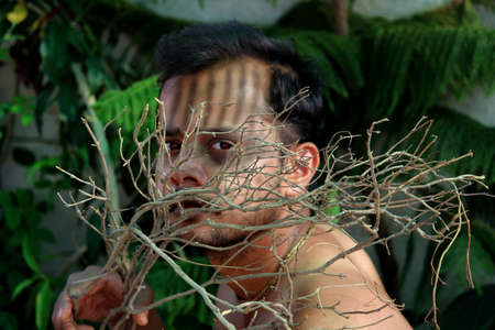 naked spooky man in halloween zombie party with holding dry branch falling background