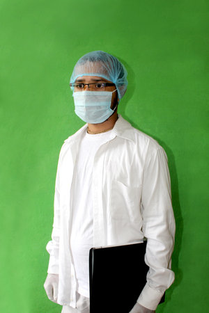young doctor in medical uniform with a protective face mask and a gloved holding patient file in covid-19, corona virus.の写真素材