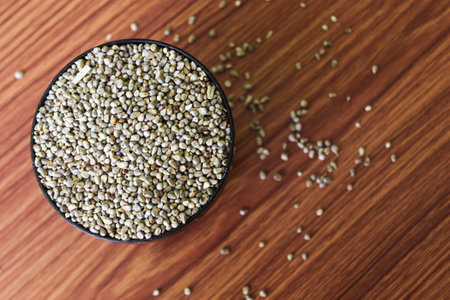 Organic Pearl Millet (Pennisetum glaucum) or Bajra, in a bowl. Isolated on a brown wooden...