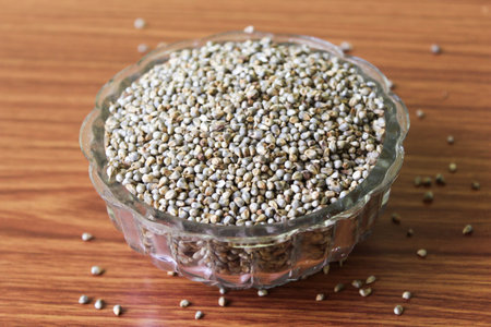 Pearl Millet (Pennisetum glaucum) or Bajra, in a bowl. Isolated on a brown wooden background....