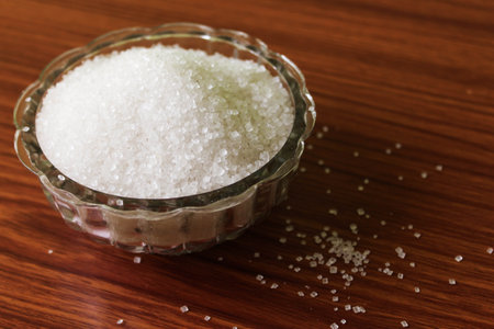 sugar in a glass bowl on a wooden table, closeup