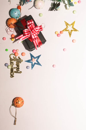Season's greetings scene. Christmas decorations,gift boxes with red ribbons, Ñhristmas balls, rustic star, holly berries, frosty spruce branches, confetti on white backdrop, selective focus with blurの写真素材