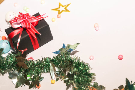 Season's greetings scene. Christmas decorations,gift boxes with red ribbons, Ñhristmas balls, rustic star, holly berries, frosty spruce branches, confetti on white backdrop, selective focus with blurの写真素材