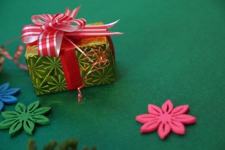 Season's greetings scene.Share your warm wishes with this image idea.view of magnificent gift box with ribbon, sparkling ornaments, frosty fir, ball, cone on green backdrop, ready for personalized adの写真素材