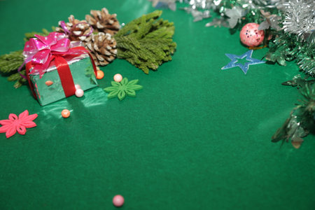 Season's greetings scene.Share your warm wishes with this image idea.view of magnificent gift box with ribbon, sparkling ornaments, frosty fir, ball, cone on green backdrop, ready for personalized adの写真素材