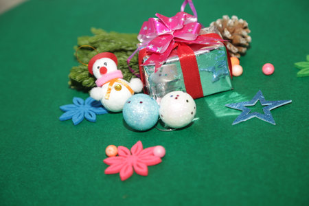 Season's greetings scene.Share your warm wishes with this image idea.view of magnificent gift box with ribbon, sparkling ornaments, frosty fir, ball, cone on green backdrop, ready for personalized adの写真素材