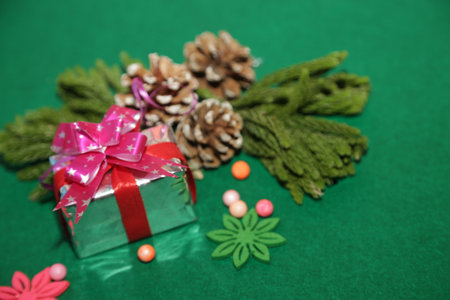 Season's greetings scene.Share your warm wishes with this image idea.view of magnificent gift box with ribbon, snowman, sparkling ornaments, frosty fir, ball, cone on green backdrop, ready for personalized adの写真素材