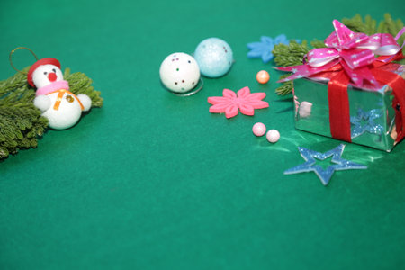 Season's greetings scene.Share your warm wishes with this image idea.view of magnificent gift box with ribbon, snowman, sparkling ornaments, frosty fir, ball, cone on green backdrop, ready for personalized adの写真素材