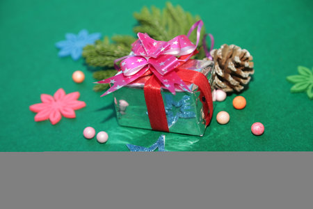 Season's greetings scene.Share your warm wishes with this image idea.view of magnificent gift box with ribbon, sparkling ornaments, frosty fir, ball, cone on green backdrop, ready for personalized adの写真素材