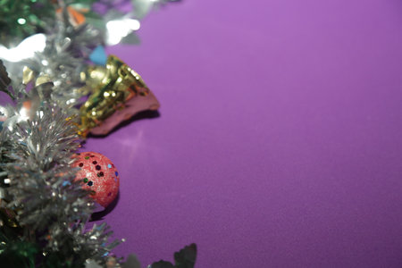Season's greetings scene. Christmas decorations, balls, rustic star, holly berries, frosty spruce branches, confetti on purple backdrop, perfect for messages or promoの写真素材