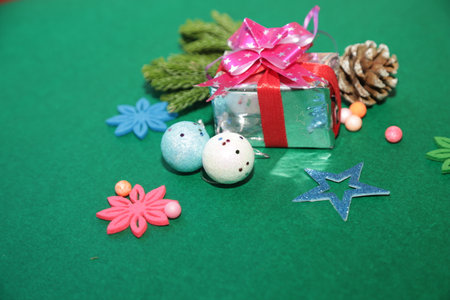 Season's greetings scene.Share your warm wishes with this image idea.view of magnificent gift box with ribbon, sparkling ornaments, frosty fir, ball, cone on green backdrop, ready for personalized adの写真素材