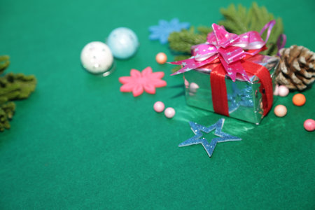 Season's greetings scene.Share your warm wishes with this image idea.view of magnificent gift box with ribbon, snowman, sparkling ornaments, frosty fir, ball, cone on green backdrop, ready for personalized adの写真素材