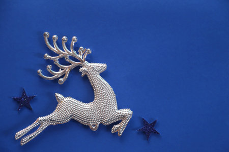 Beautiful christmas silver deer close up isolated on a blue background.Adorable reindeer with presents for christmas decoration.の写真素材