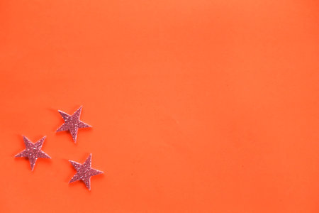 Season's greetings scene. Sparkling stars on a orange background. Flat lay. orange backdrop text or...