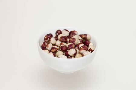 close up of dried white-brown beans in white bowl