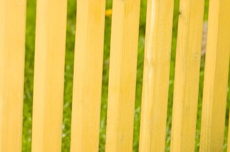 background - detail of yellow wooden fence, grass visible behindの写真素材
