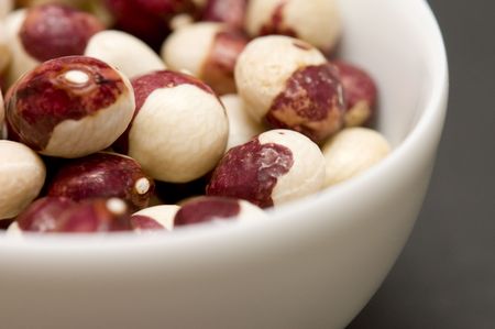 close up of dried white-brown beans in white bowl