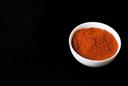 dried red paprika in white bowl on black backgroundの写真素材