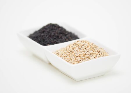 black and white sesame seeds in white bowlの写真素材