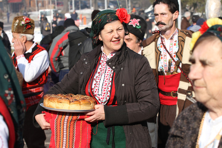 Folklore ensemble with traditional costumes dance horo with ritual bread (loaf) during the...