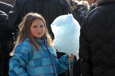 Little girls eat cotton candy on a town fair in Pernik, Bulgaria  Jan 27,2018. Toothache and unhealthy food. Diet, fat and calories.のeditorial素材