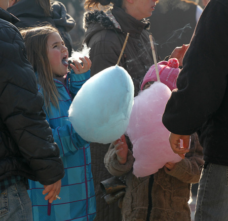 Little girls eat cotton candy on a town fair in Pernik, Bulgaria  Jan 27,2018. Toothache and unhealthy food. Diet, fat and calories.のeditorial素材