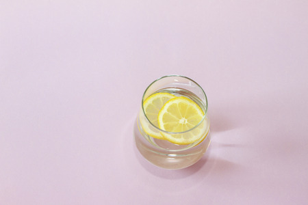 Glass of water and lemon. Glass of pure water and fresh organic lemon isolated on purple background....