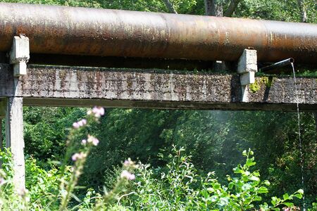 Rusty, cracked pipes spray water in nature. Water supply network.の写真素材