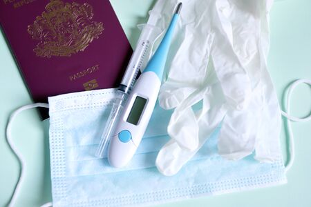 Coronavirus prevention concept. Protective mask, gloves, thermometer, syringe and passport for...