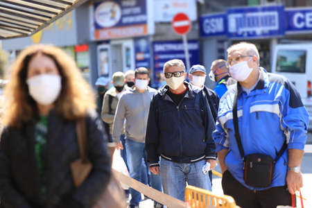 With strict control and disinfection people, wearing face masks for prevention of coronavirus COVID-19 disease, in a line for entry in a marketplace in Sofia, Bulgaria on 04/14/2020.のeditorial素材