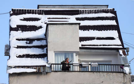 Person are cleaning a very snowy balcony and a rooftop of snow in Sofia, Bulgaria - DEC 01, 2020の写真素材