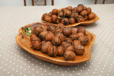 Fresh harvest walnuts with shells and water drops in wooden bowl. Walnuts details