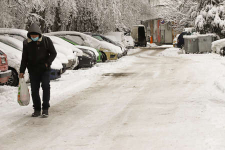 People walk on unclean street covered with danger ice after snowfallの写真素材