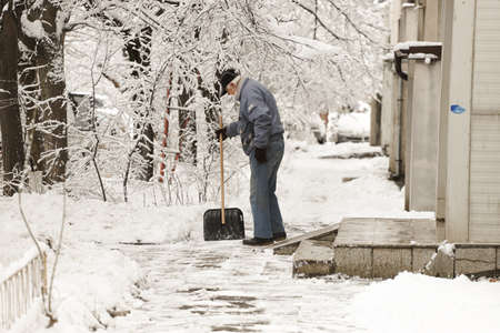 People clean snow and ice from sidewalkの写真素材