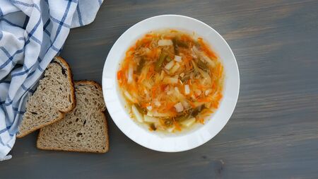 Traditional russian food. Soup shchi with sour cabbage in a white plate and bread on a gray background. Top viewの写真素材
