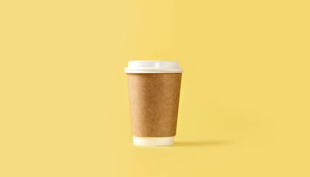 Paper coffee cup with white lid on yellow backgroundの写真素材