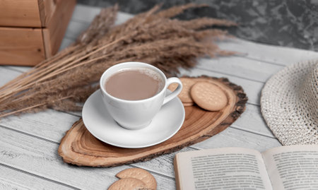 A cup of americano or espresso with biscuits, book nd reeds. Top view