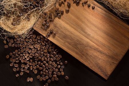 Black roasted coffee grains. On wood background. Top view and frame for inscriptions.