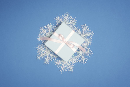 Decorative white snowflake and new year gift box on blue background. Christmas Flat lay.の写真素材