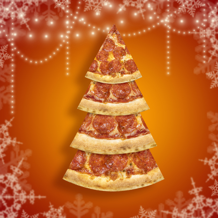 Xmas pizza slice in shape of Christmas tree with snowflake on orange background.の写真素材