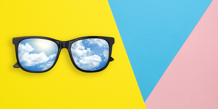 Creative layout made of sunglasses with reflection sky and cloud on multicolored paper background. Summer concept. Sunglasses mockup as design element vacation and journeys top view. Minimal concept.の写真素材