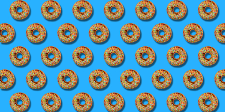 Creative pattern donuts colorful flat lay on pastel blue background. Minimal sweet food concept....