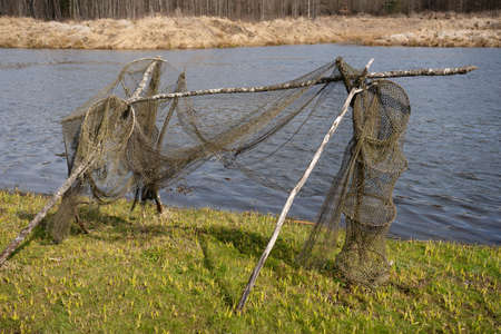 Ancient fishing nets are dried on the shore of the lake on wooden supports