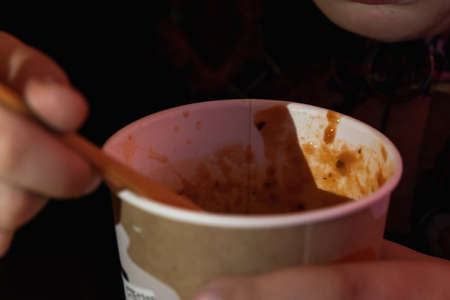 A boy spoons tomato soup - mashed potatoes in the dark. Close-up.