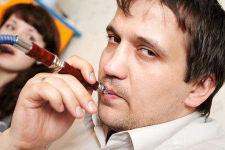 The man lights up a hookah at evening-party