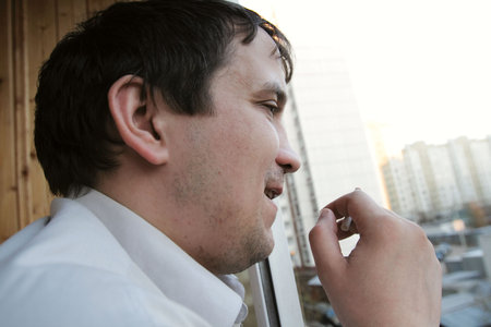 The man with cigarette looks out of the window 