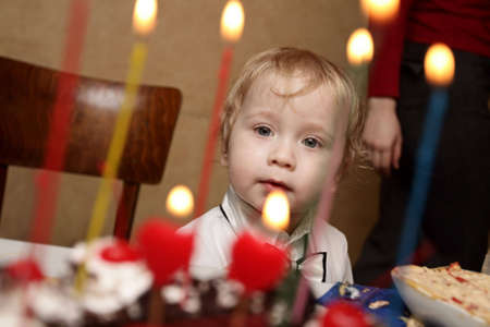 The boy look at cake with candlesの写真素材