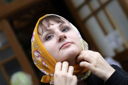 The girl ties a kerchief round one's headの写真素材