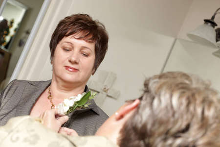 Woman pinning boutonniere on mother of the bride, weddingの写真素材